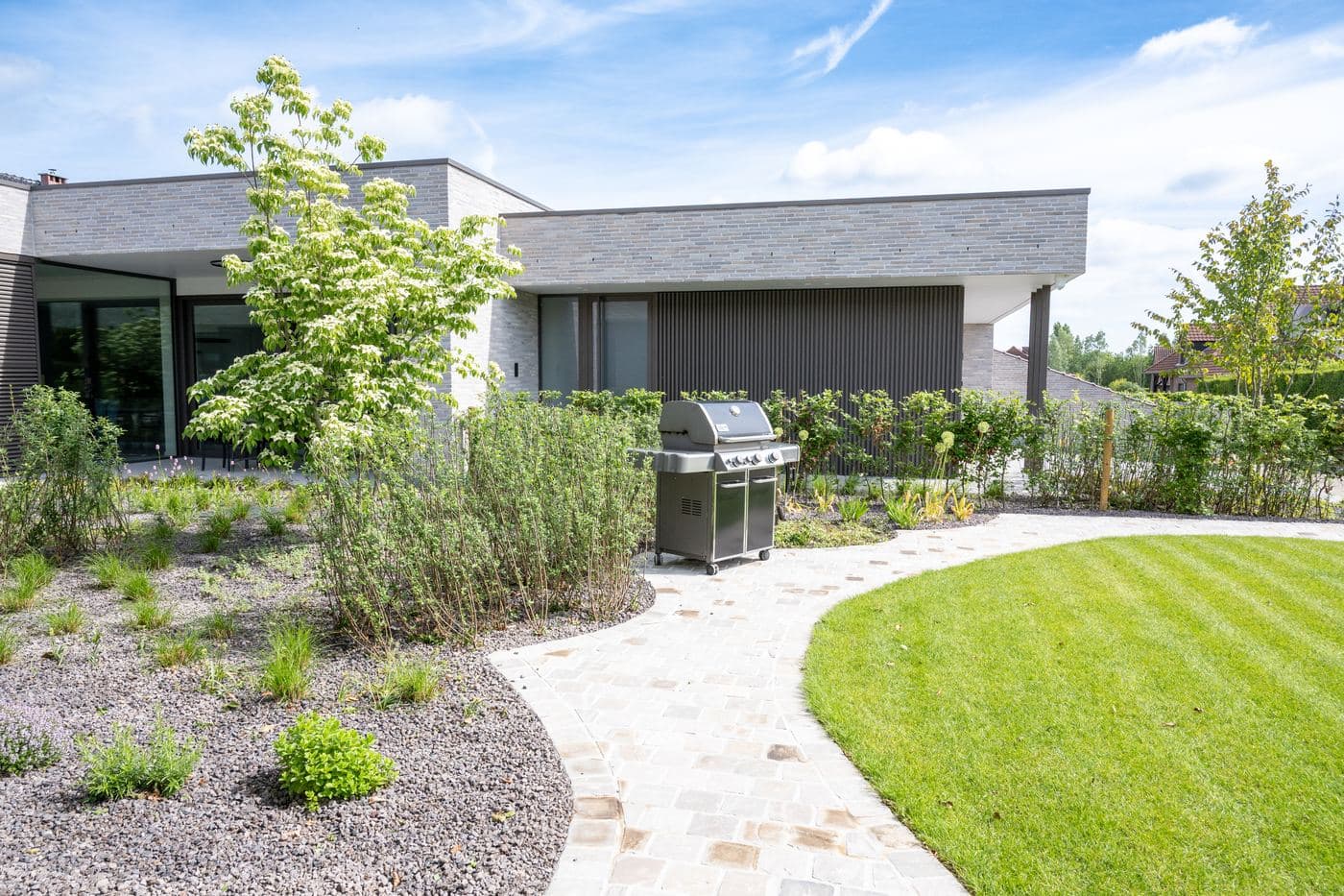 Nieuw aangelegde tuin met slingerend pad en jonge beplanting