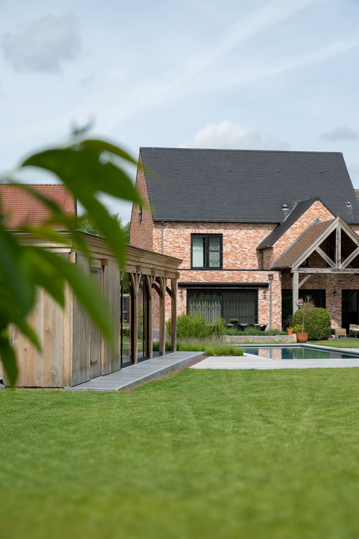 Tuin met zwembad en houten bijgebouw bij een bakstenen woning