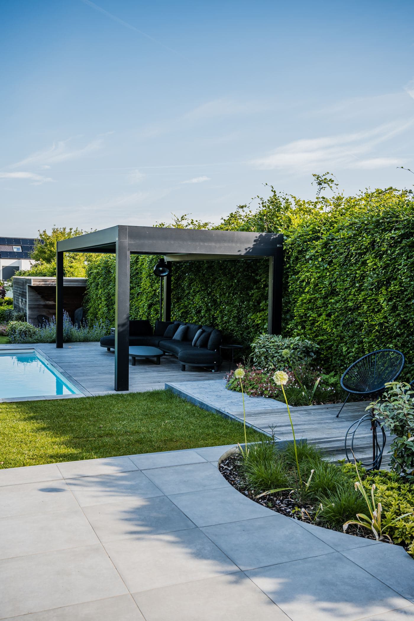 Pergola met loungezetel naast een smal zwembad
