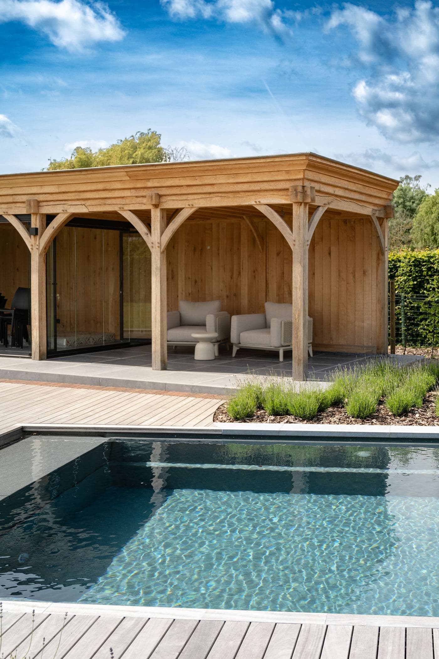 Houten poolhouse met loungezetels aan het zwembad